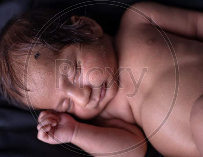 Cute Little Baby Sleeping Calmly Over a black Cloth Background