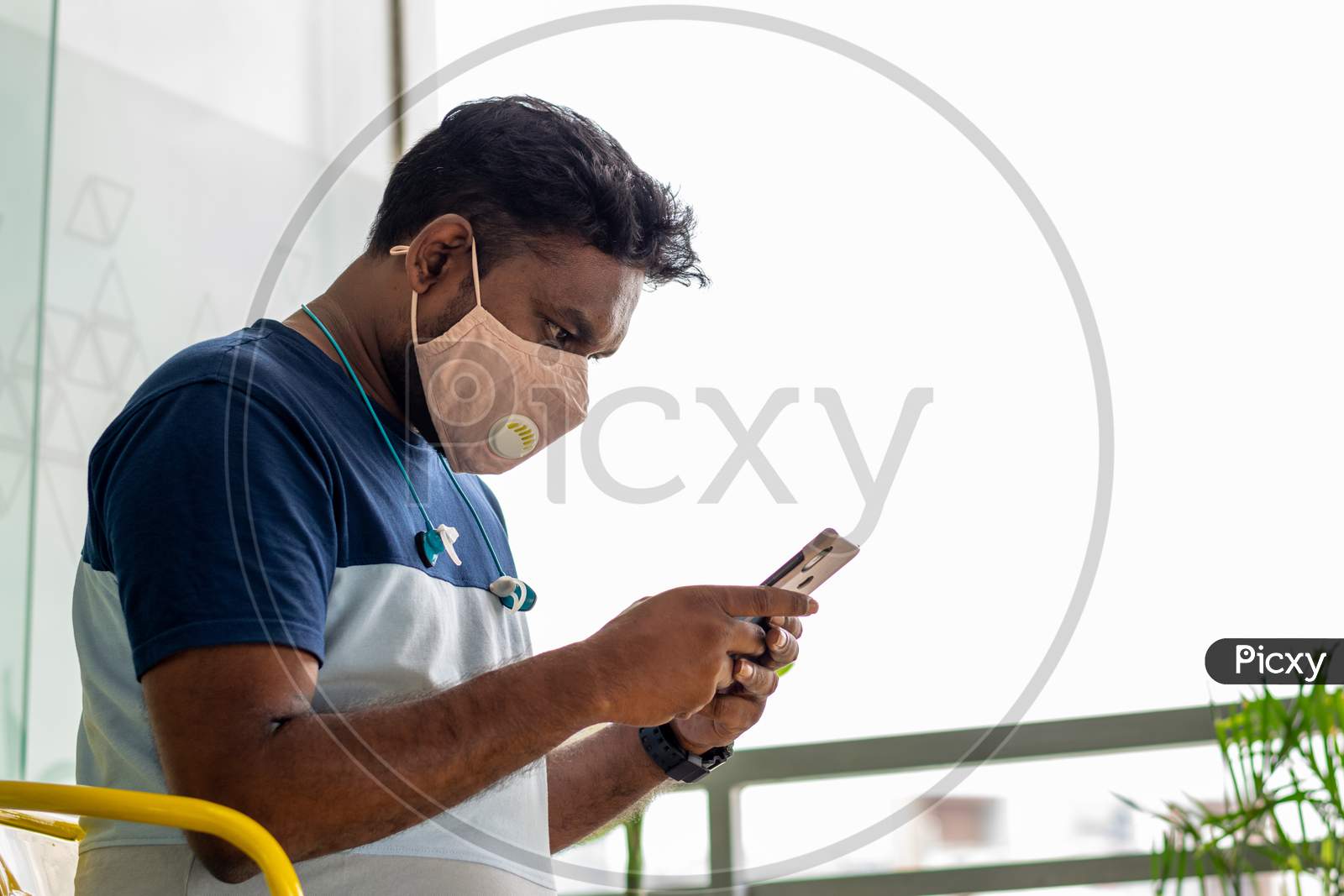 A person using his phone and wearing a mask to protect himself from Novel Corona Virus Covid-19