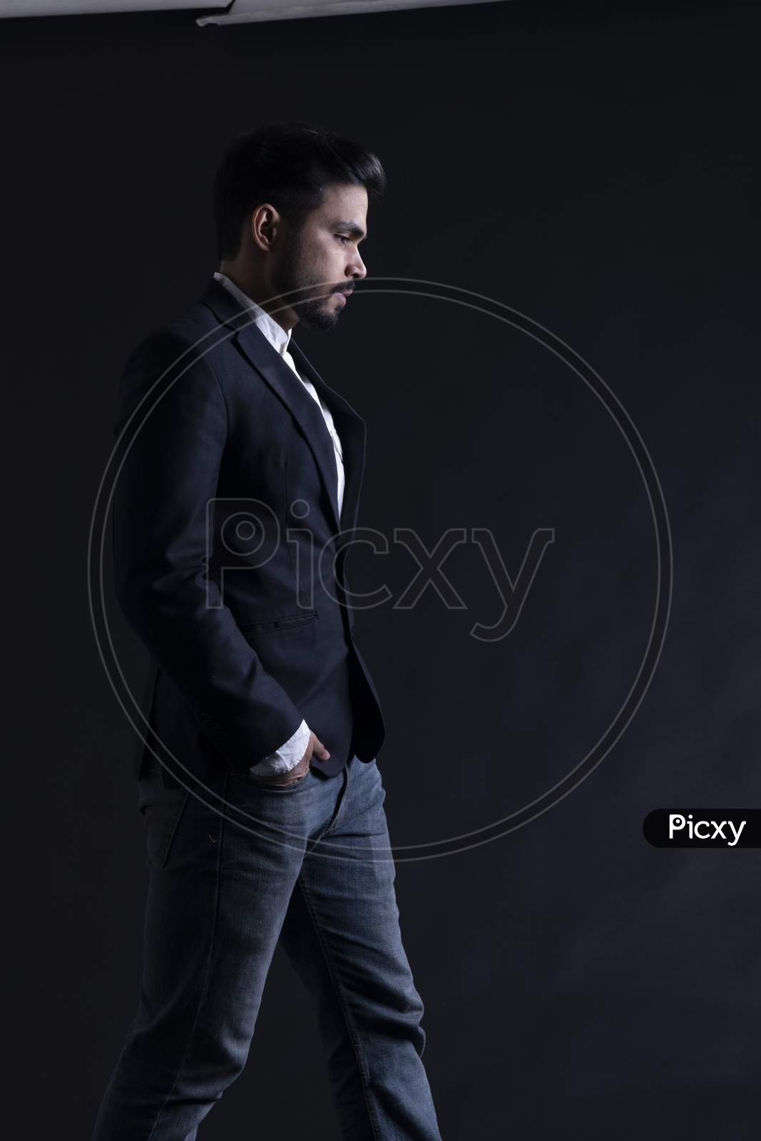 Indian Young Male Model Posing Wearing A Suite Over An Black grunge wall Background