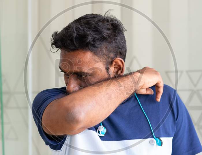 A person coughing into his elbow to prevent spreading germs