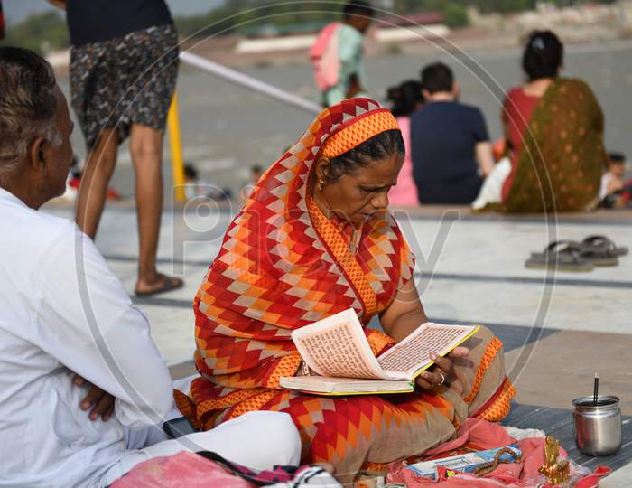 Indian Woman Reading Hindu Holy Books  By Sitting On Ganges River Bank  in Rishikesh