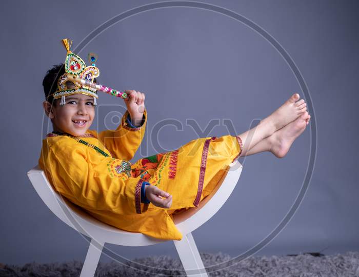 Young Indian Boy Dressed like Lord Sri Krishna And Posing Over an Gray Background
