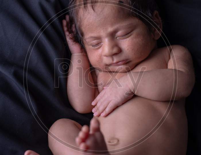 Cute Little Baby Sleeping Calmly Over a black Cloth Background