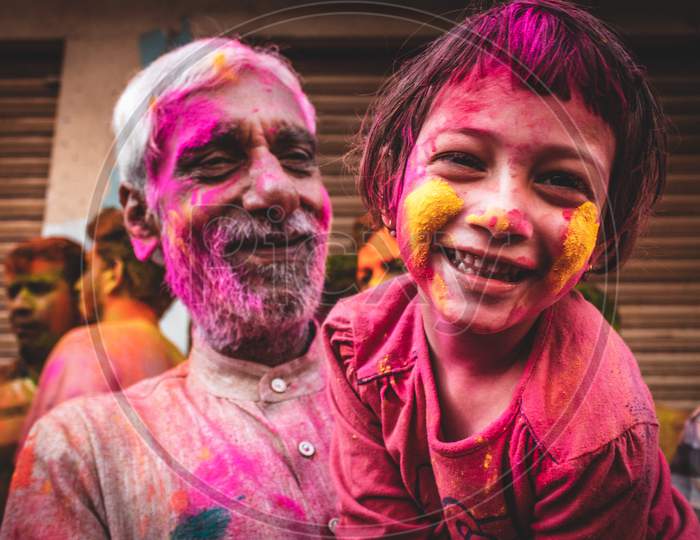 Portrait of a girl playing holi with her grandfather