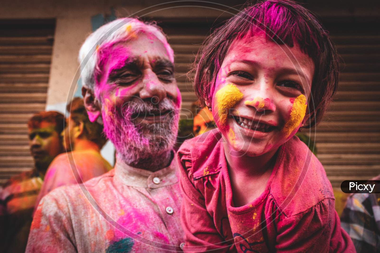 Portrait of a girl playing holi with her grandfather