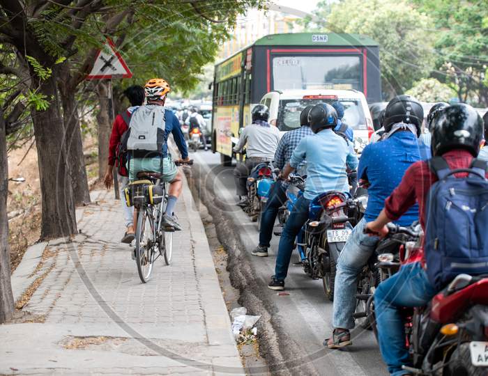 A man rides his bike on the footpath as the traffic halts on the road