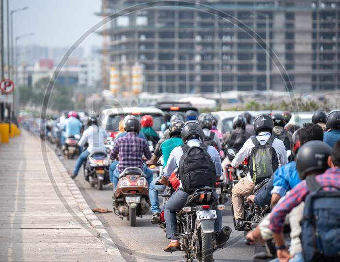 Bikers wearing helmets on a flyover in a slow moving traffic