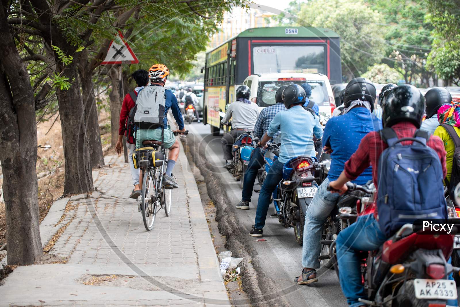 A man rides his bike on the footpath as the traffic halts on the road
