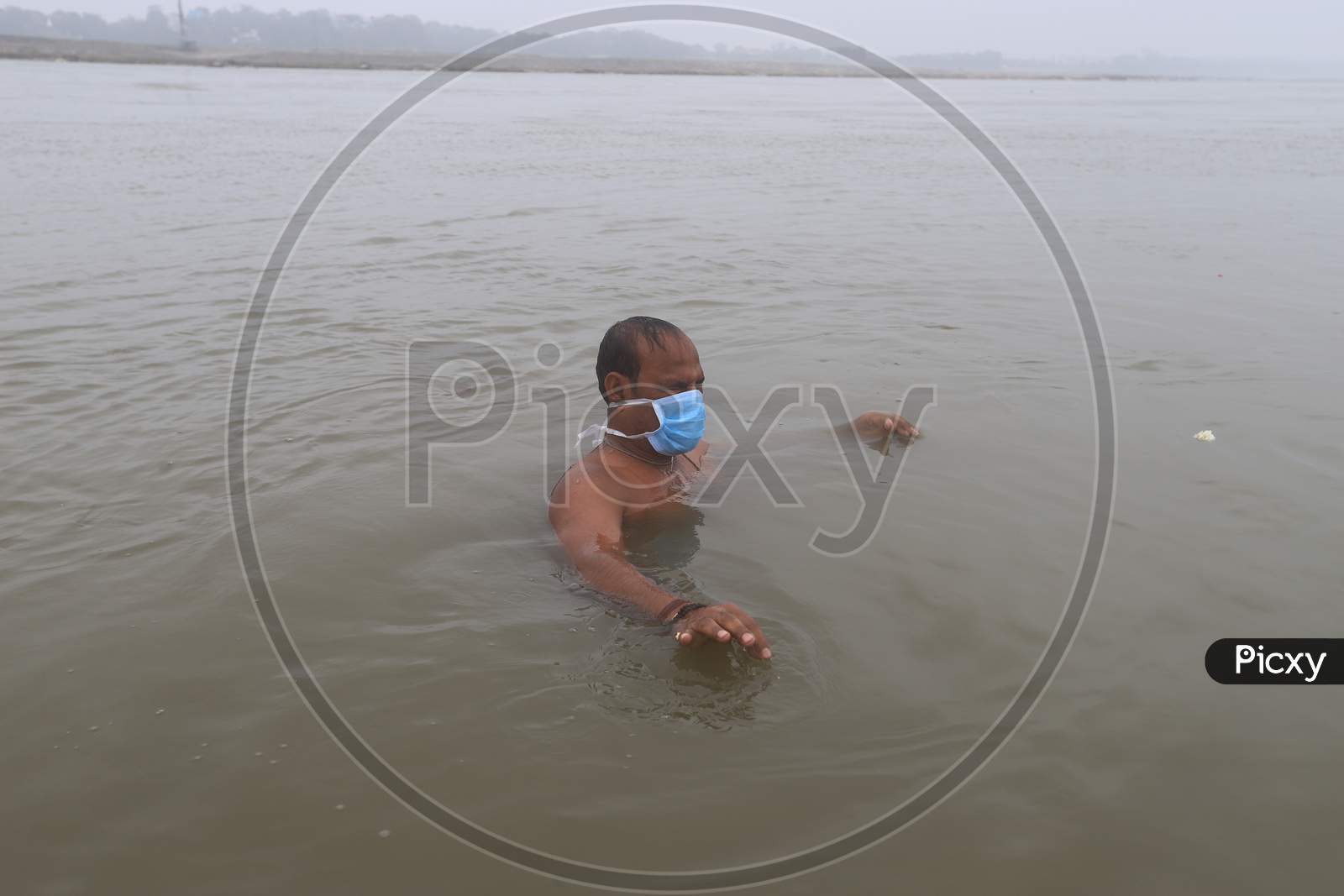 A Devotee Taking Holy Bath in Triveni Sangam River wearing Surgical Mask At Prayagraj