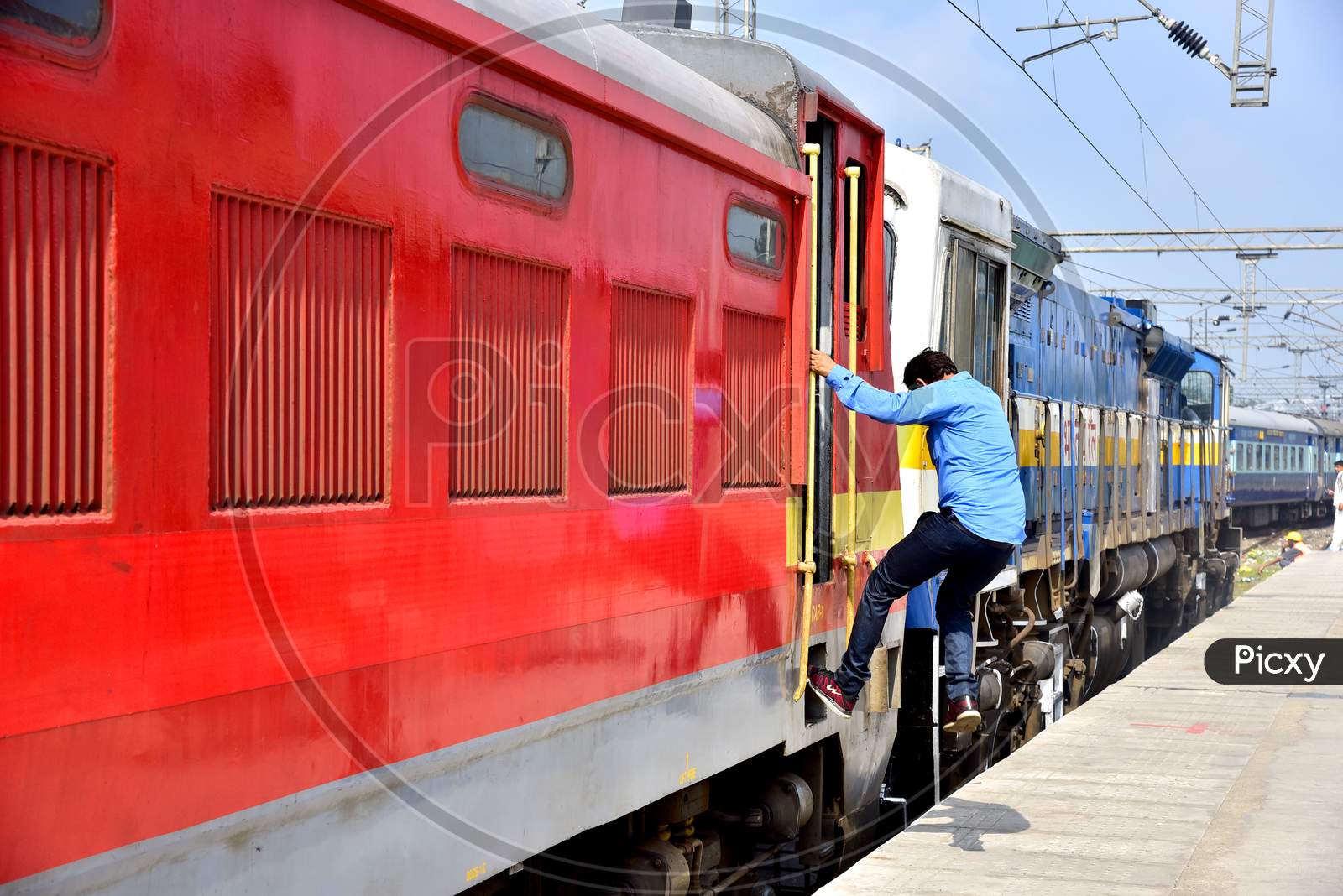 A Man Boarding a Running Train From a Railway Station Platform