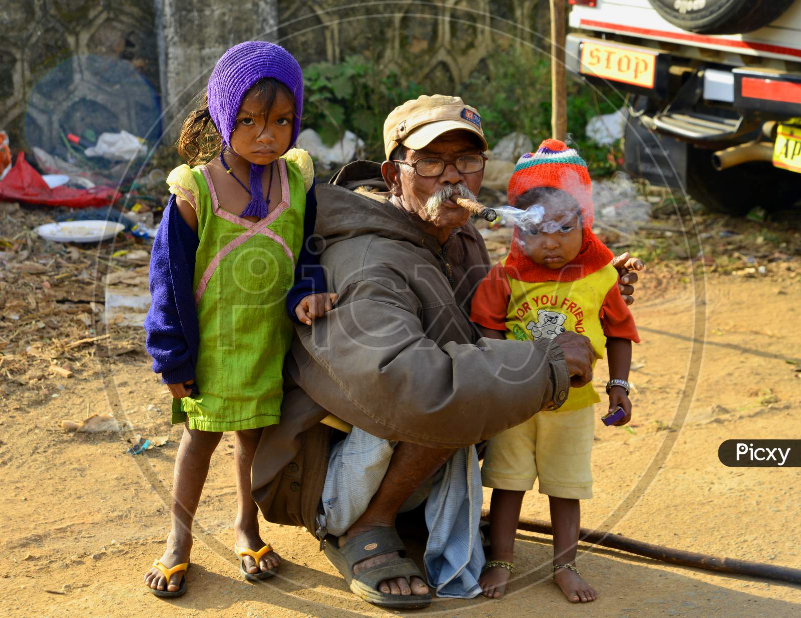 An Old Man Smoking Tobacco With Children With Him