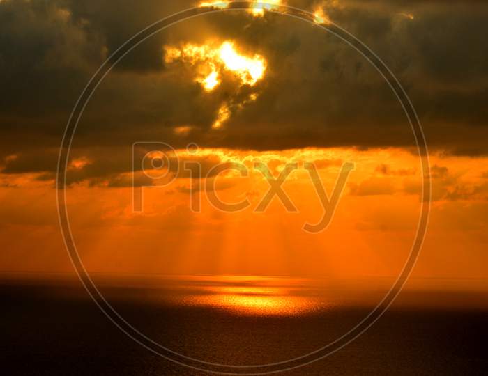 Sunset Golden Sky With Dark Clouds And Sun Rays Falling Over Sea In Visakhapatnam