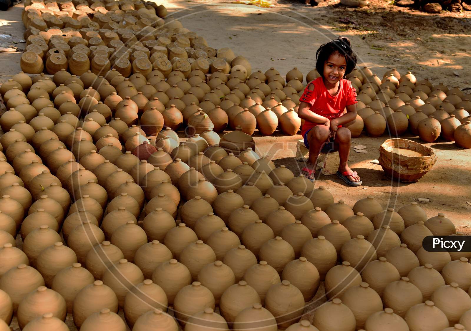 A Girl Child Sitting At  Pottery Work Shop With Newly Prepared Pots