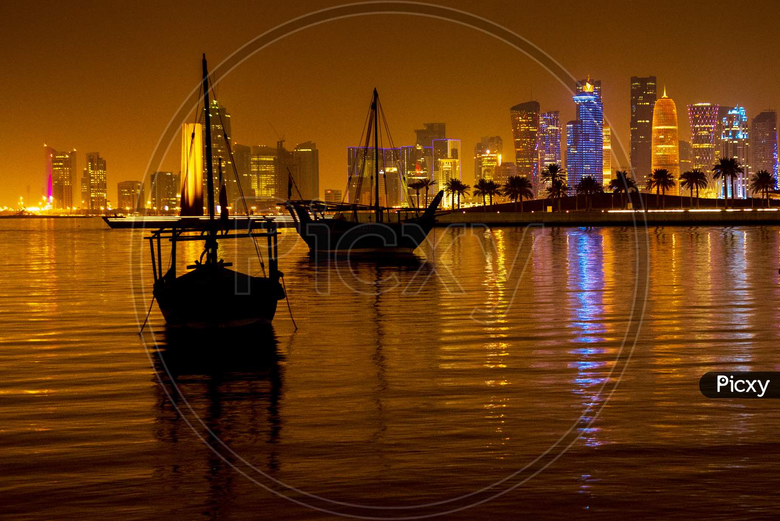Silhouette Of Boats At West Bay Doha With Urban Buildings Background In Night Lights Background