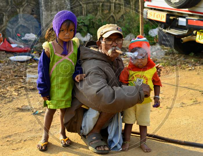 An Old Man Smoking Tobacco With Children With Him