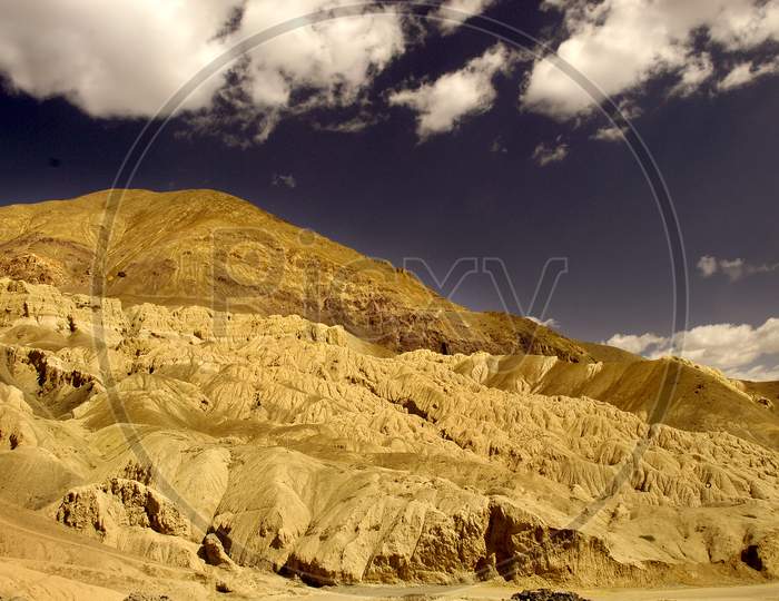 Sedimentary Sand  Mountains With Cotton Clouds in Sky As Background