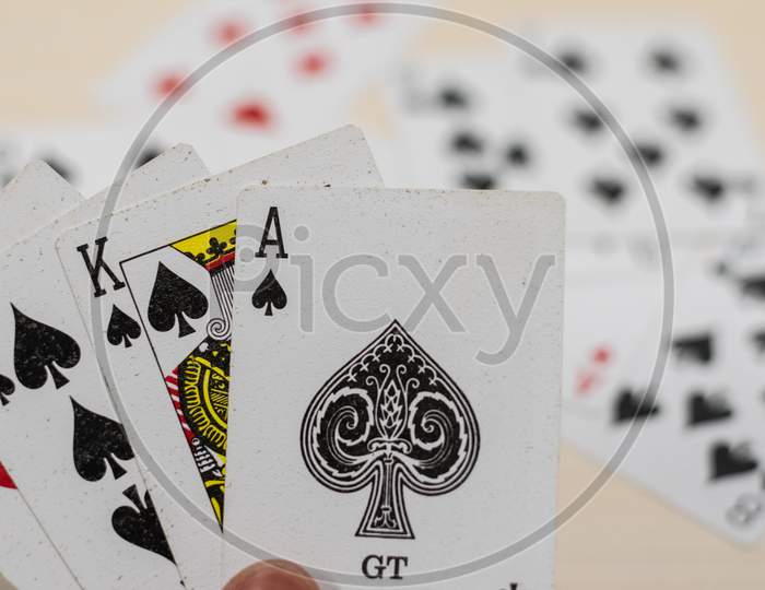 ace king and ten of spades playing cards with background of other cards