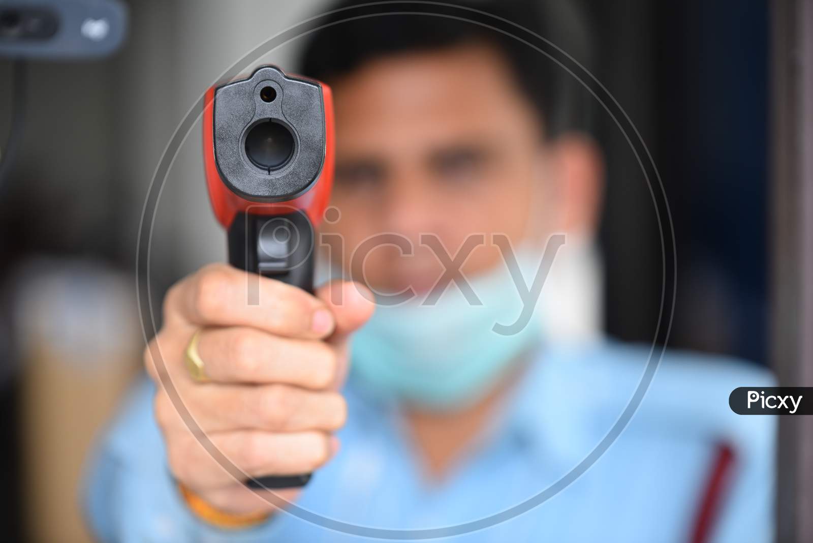 A security personnel using Infrared Thermometer using Laser Radiation to find out the Human Body temperature as fever is one of the symptoms of COVID19 Corona Virus