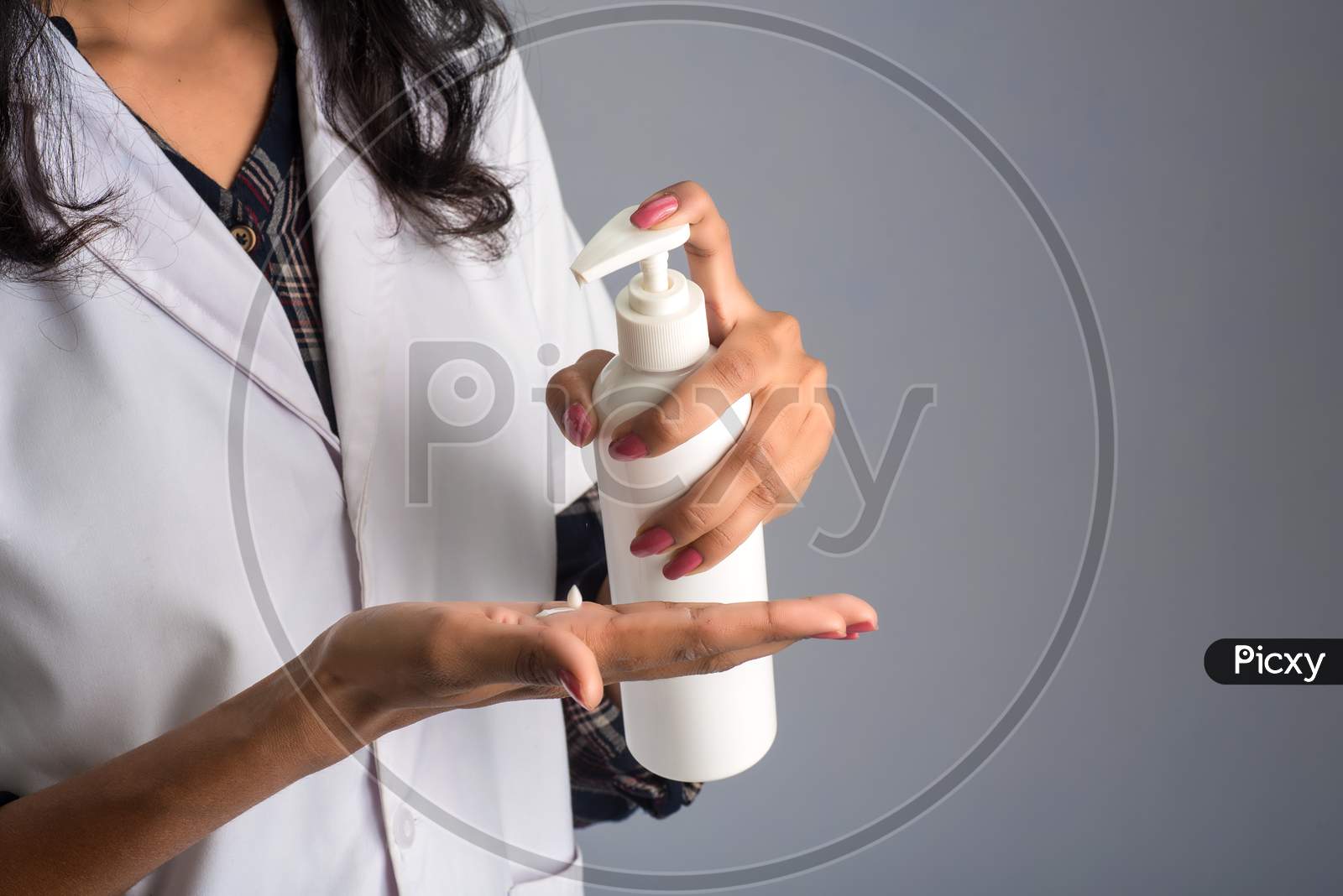 Portrait Of Woman Doctor Using A Sanitizing Gel From A Bottle For Hands Cleaning.