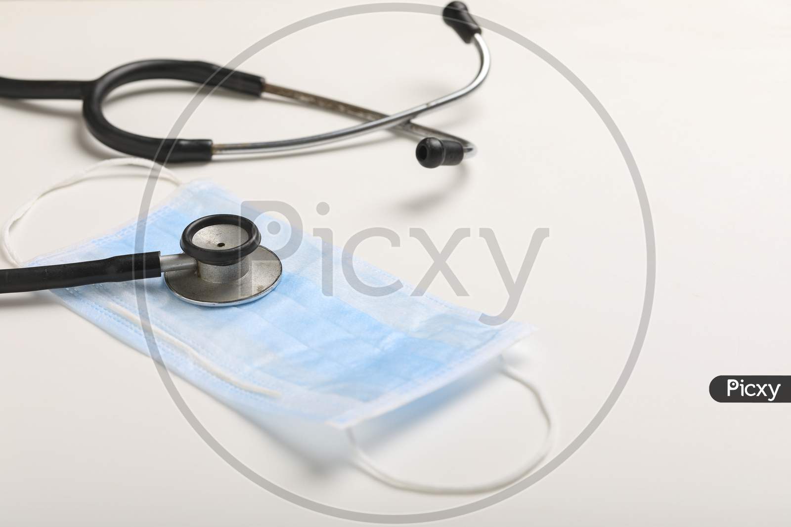 Anti Viral Surgical mask For Safety of COVID 19 or Corona Virus With Stethoscope Over a White Background