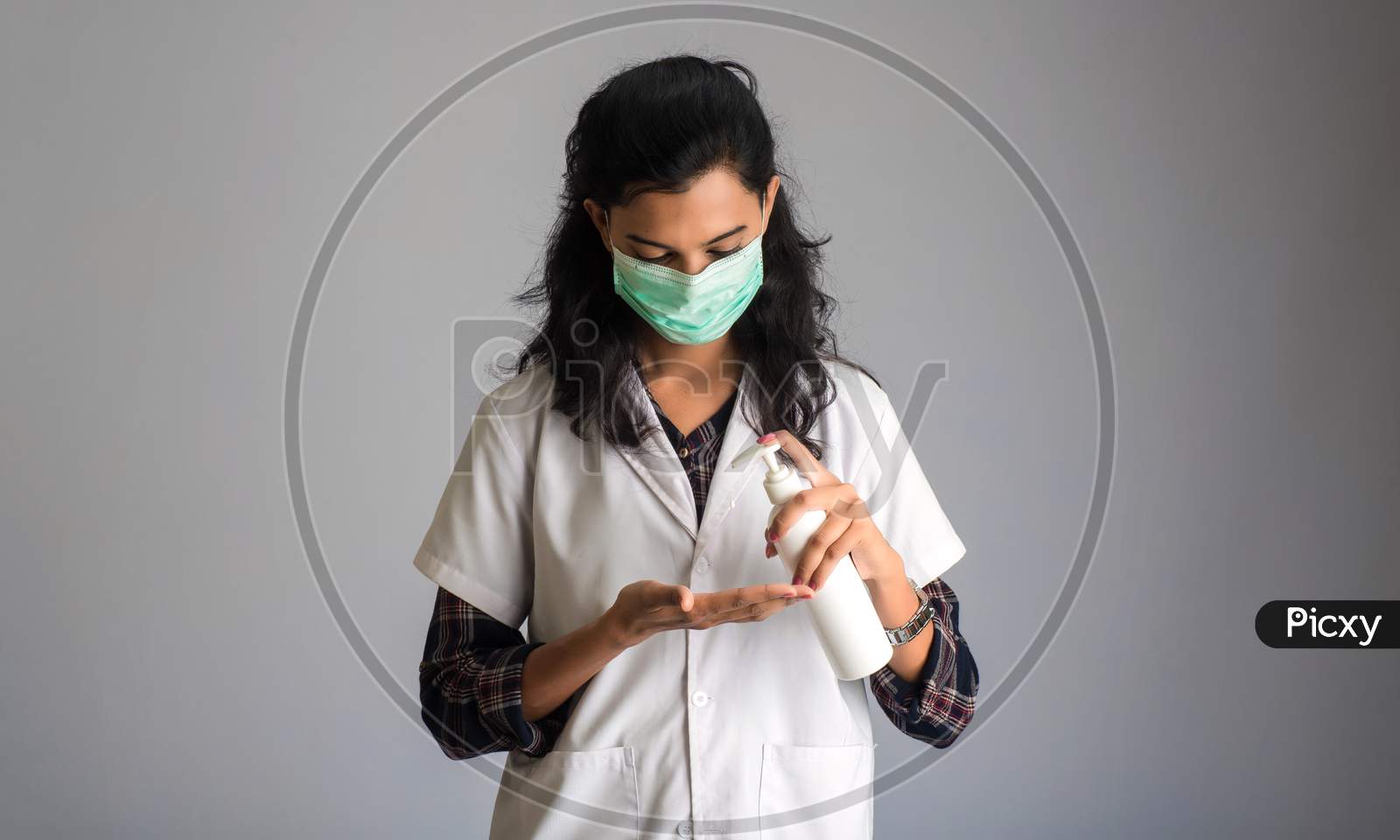 Portrait Of Woman Doctor Using A Sanitizing Gel From A Bottle For Hands Cleaning.