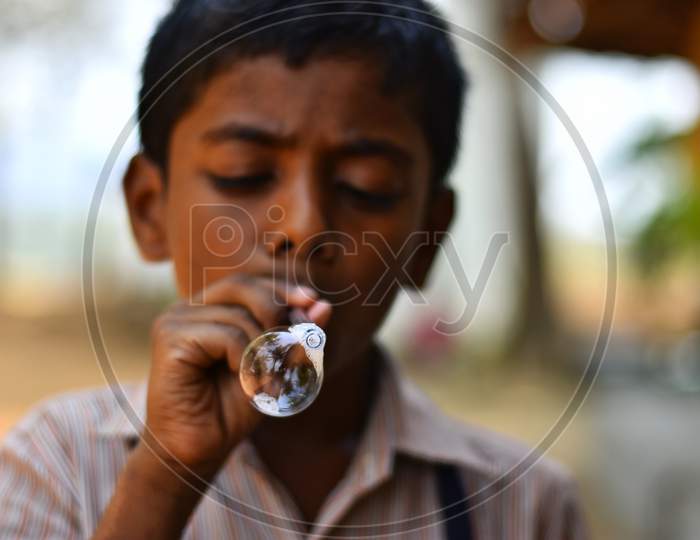 A kid blowing water bubbles.