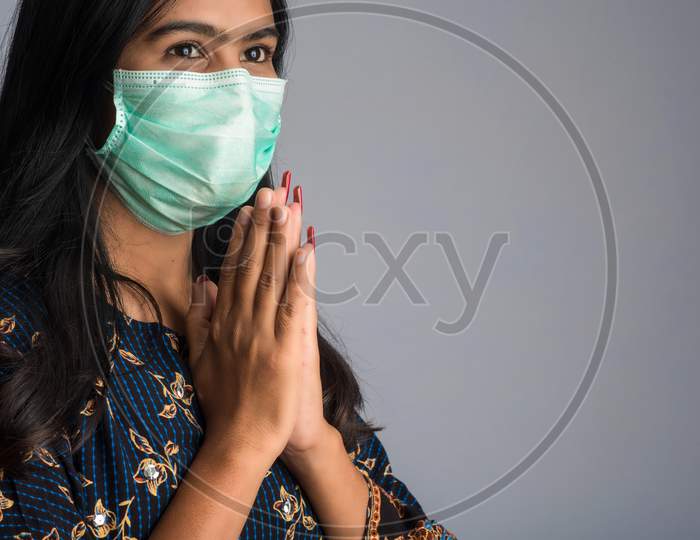 Portrait Of A Girl Wearing A Medical Mask Doing Greeting With Namaste Gesture.
