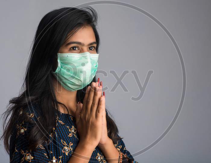 Portrait Of A Girl Wearing A Medical Mask Doing Greeting With Namaste Gesture.
