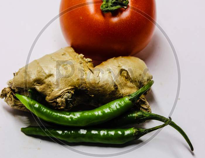 Ginger , Green Chilies And Tomato Over An Isolated White Background