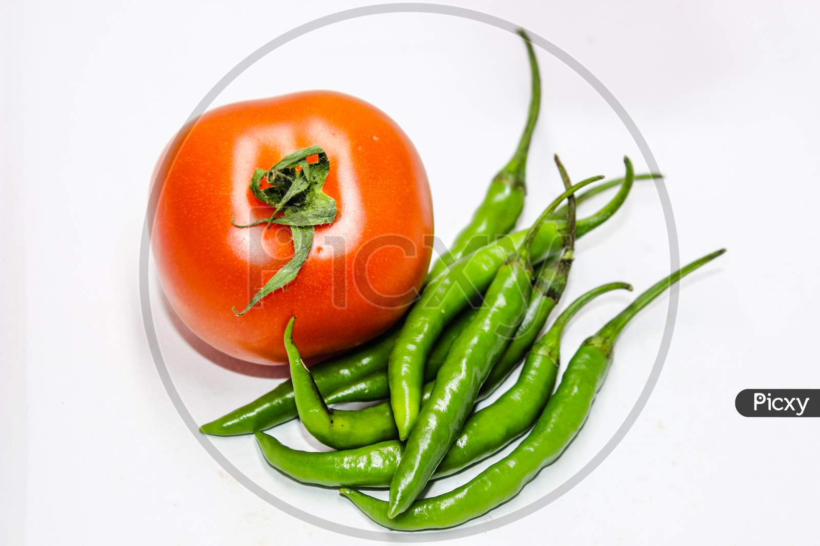 Green Chillies And Tomato Over An Isolated White Background