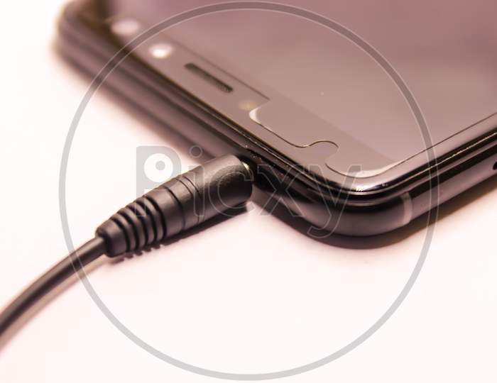 Earphones Jack Connected To an Smart Phone Over an Isolated White Background