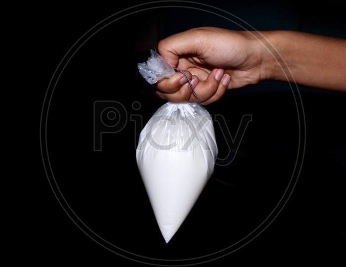 A Man Holding a Milk Packet in Hand Over an isolated Black Background