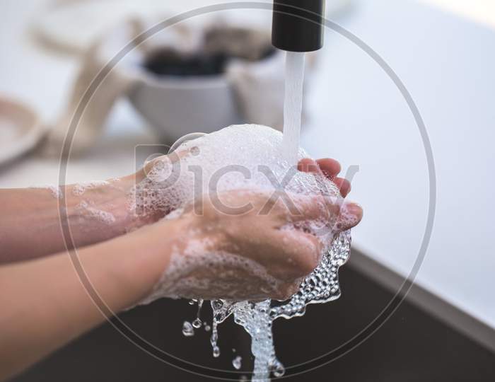 People Washing Hands With Running Water Under a Tap Amidst Of Corona Virus Or COVID 19 Outbreak