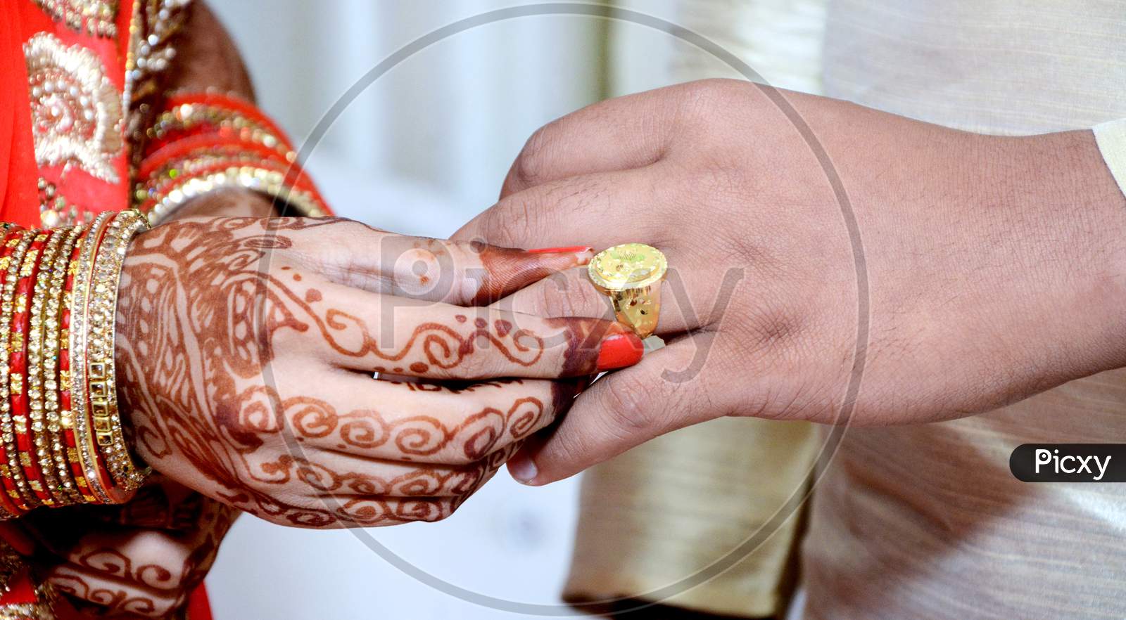 Indian Bride Putting A Wedding Ring On Groom'S Finger
