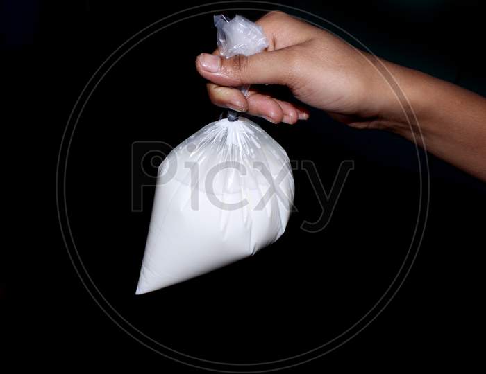 A Man Holding a Milk Packet in Hand Over an isolated Black Background