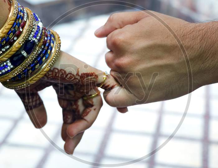 Closeup Image Of A Man'S And Woman'S Hands Holding Little Fingers Of Each Other Isolated Over White Wall Background.