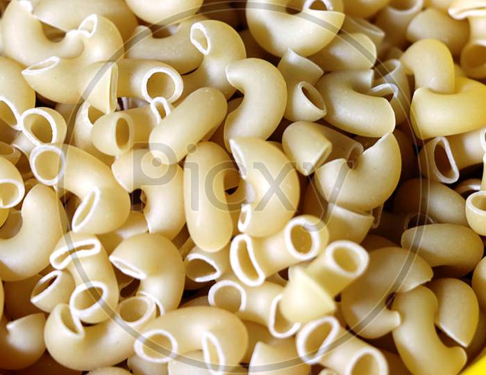 Pasta Raw Closeup Background. Delicious Dry Uncooked Ingredient For Traditional Italian Cuisine Dish.