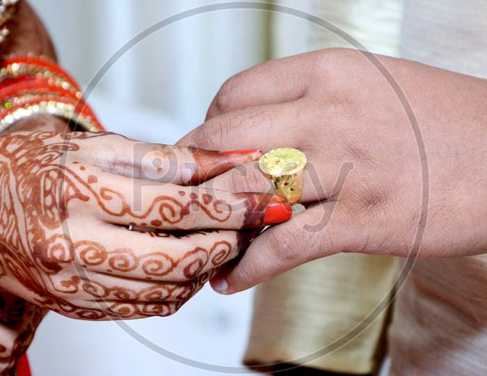 Indian Bride Putting A Wedding Ring On Groom'S Finger
