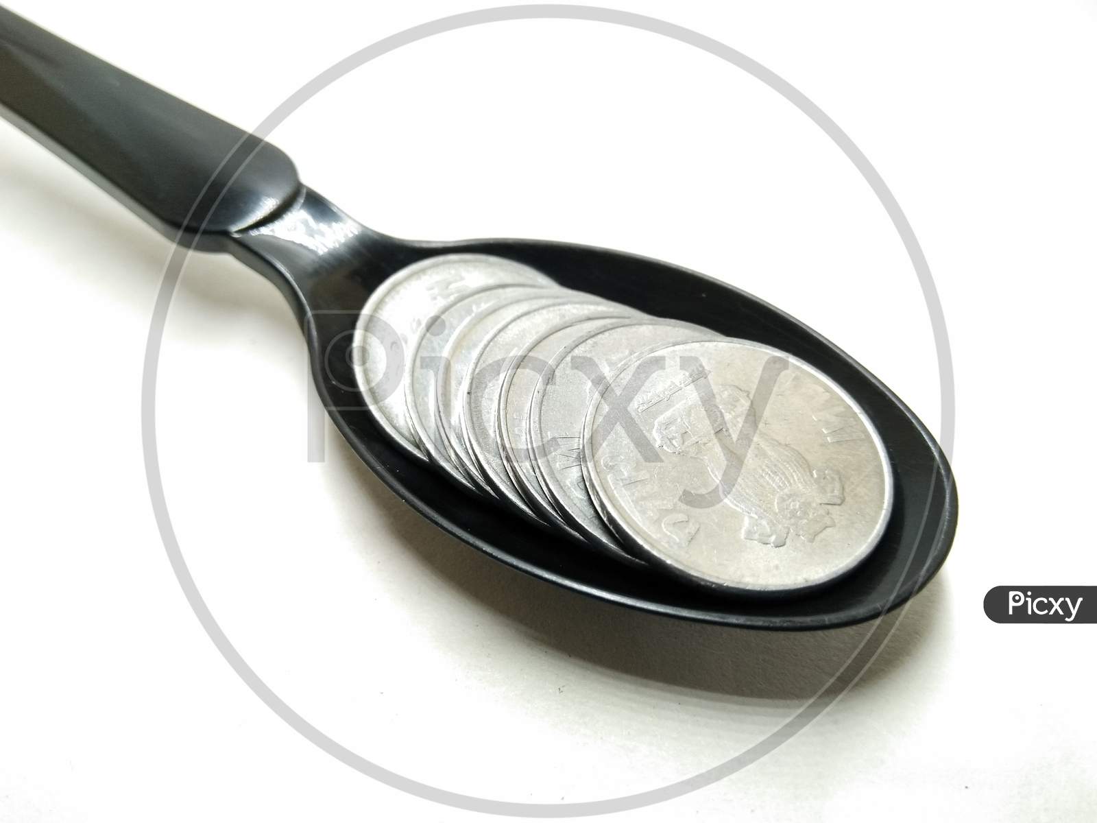 Indian Currency Rupee Coin in Spoon  Over an Isolated White Background
