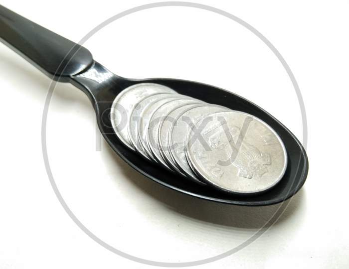 Indian Currency Rupee Coin in Spoon  Over an Isolated White Background