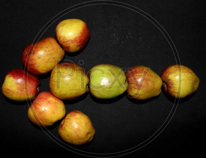 Arrow Mark To Left With Apples Over An Isolated Black Background