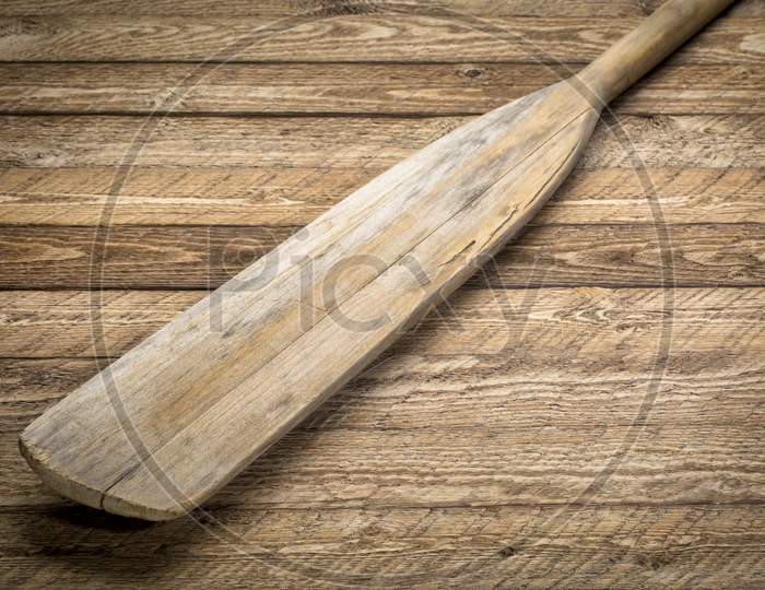 Blade Of Vintage Wooden Canoe Paddle Against Weathered Wood Background