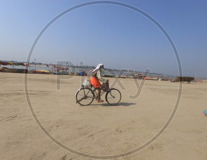 An Indian Baba Or Sadhu riding Bicycle At Ganga River Bank