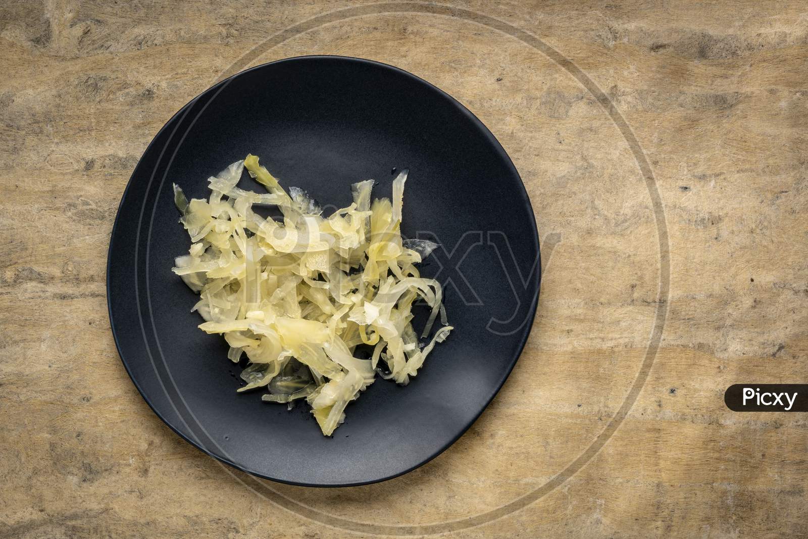 Black Plate Of Sauerkraut Against  Bark Textured Paper Background, Probiotics Concept - Fermented Food Good For Gut Health