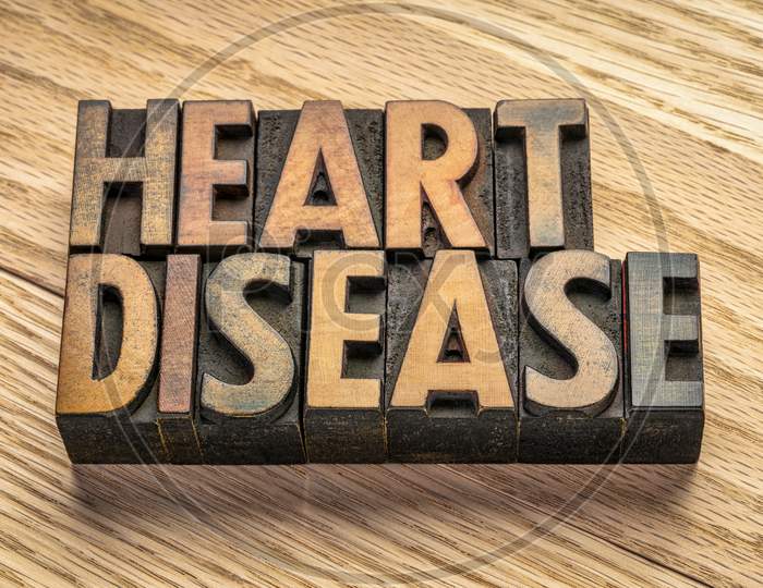 Heart Disease Word Abstract In Vintage Letterpress Wood Type Blocks Against Grained Wood Planks, Health And Well Being Concept