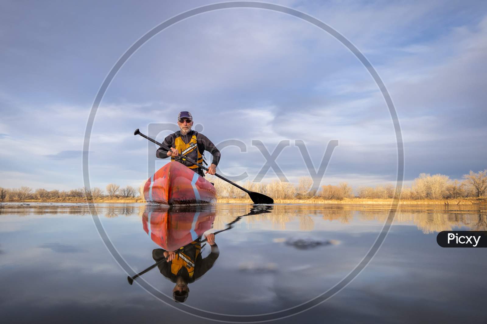 Senior Male Paddler In A Wetsuit Is Paddling A Stand Up Paddleboard On A Calm Lake In Colorado, Winter Or Early Spring Scenery, Low Angle Action Camera View, Recreation, Fitness And Training Concept