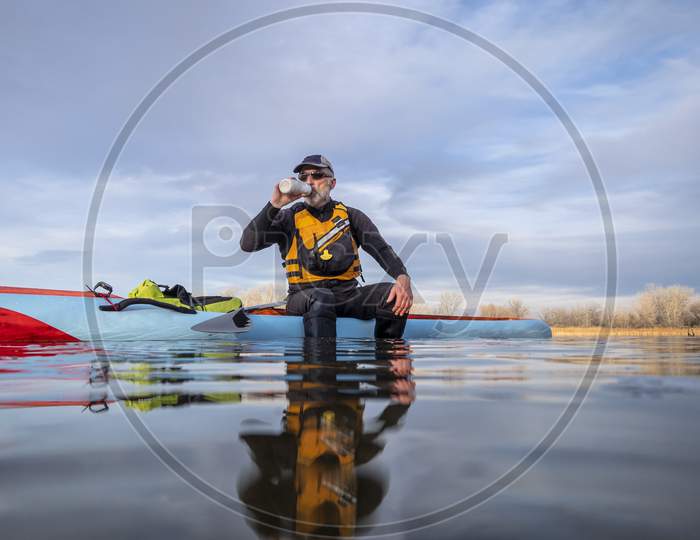 Senior Male Paddler Is Drinking Water During  Workout On A Stand Up Paddleboard, Lake In Colorado, Low Angle Action Camera View,  Recreation, Fitness And Training Concept