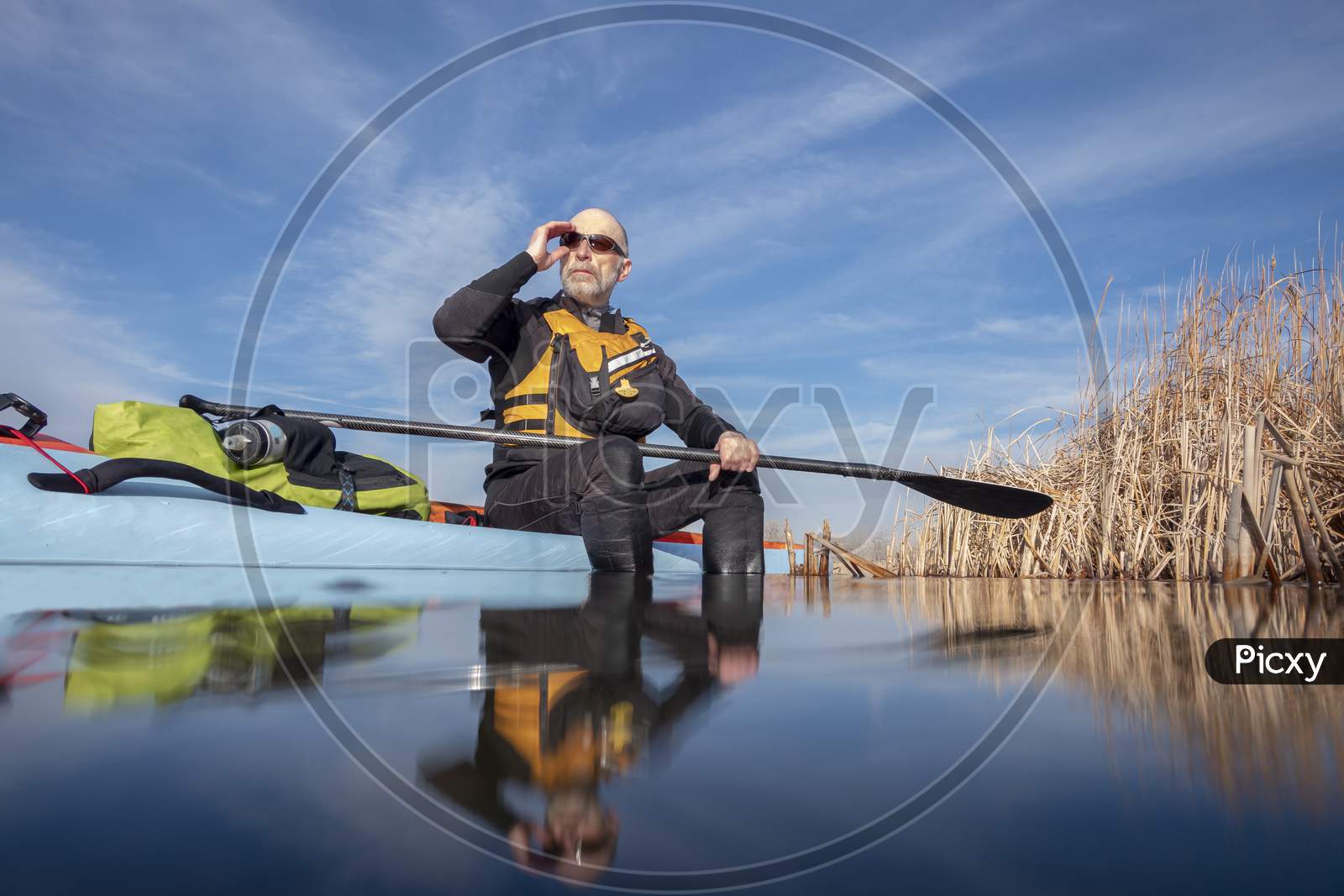 Senior Male Paddler Is Relaxing In The Afternoon Sun After Workout On A Stand Up Paddleboard, Lake In Colorado, Winter Or Early Spring Scenery, Recreation, Fitness And Training Concept