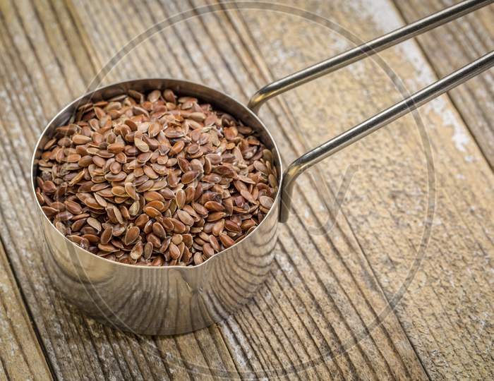 Metal Measuring Scoop Of Brown Flax Seeds Against  Grunge  Wood Background, Superfood And Healthy Eating Concept