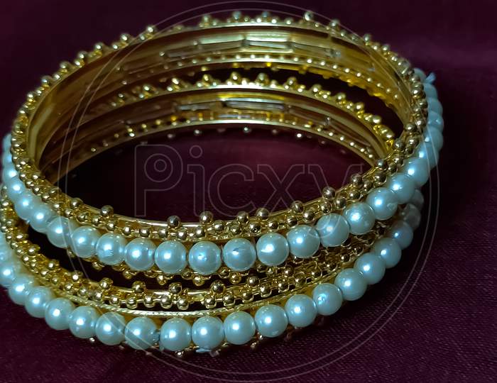 Photo of Indian jewellery pearl bangles with maroon background